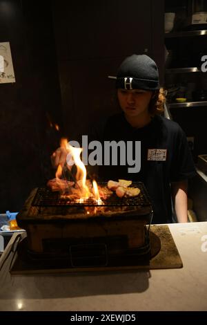 Un giovane giapponese che grigia spiedini al ristorante Washio Yakitori Izakaya a Chuocho, Kagoshima, Giappone. Foto Stock