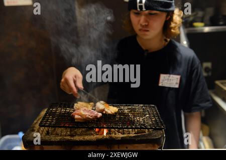 Un giovane giapponese che grigia spiedini al ristorante Washio Yakitori Izakaya a Chuocho, Kagoshima, Giappone. Foto Stock