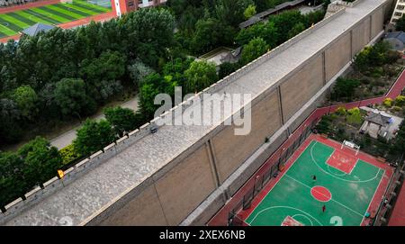 Pechino, la regione autonoma cinese Ningxia Hui. 28 giugno 2024. I residenti giocano a pallacanestro in un campo vicino alle mura della città di Yanchi County, nella regione autonoma Ningxia Hui del nord-ovest della Cina, 28 giugno 2024. Crediti: Feng Kaihua/Xinhua/Alamy Live News Foto Stock