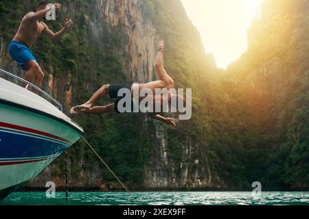 Uomo, barca e salto nel lago per l'avventura in yacht per la vela, le vacanze e le vacanze estive. Acrobazie, viaggi e turismo con gli amici in viaggio Foto Stock