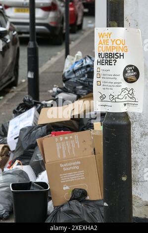 Selly Oak, Birmingham, 30 giugno 2024 - Un poster che chiede alla gente perché stanno scaricando rifiuti con rifiuti scaricati sullo sfondo. - Le strade residenziali di Birmingham sono state trasformate in discarica mentre gli studenti si spostano di casa alla fine dei loro contratti. La maggior parte degli studenti frequenta l'Università di Birmingham, che si trova a circa 800 metri dalle strade abitative terrazzate di Selly Oak. Le strade sono state acquistate principalmente da proprietari terrieri che le affittano ai laureandi con una fila di insegne "in affitto". Credito: Interrompi stampa Media/Alamy Live News Foto Stock