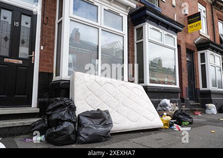 Selly Oak, Birmingham, 30 giugno 2024 - Un materasso scaricato fuori dalla struttura. - Le strade residenziali di Birmingham sono state trasformate in discarica mentre gli studenti si spostano di casa alla fine dei loro contratti. La maggior parte degli studenti frequenta l'Università di Birmingham, che si trova a circa 800 metri dalle strade abitative terrazzate di Selly Oak. Le strade sono state acquistate principalmente da proprietari terrieri che le affittano ai laureandi con una fila di insegne "in affitto". Anche alcuni residenti locali vivono nella zona, tra i giovani speranzosi e hanno soprannominato la zona "Smelly Oak". Credito: Sto Foto Stock