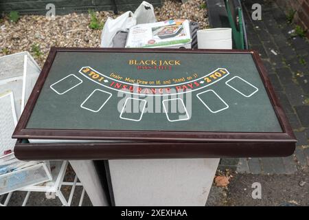 Selly Oak, Birmingham, 30 giugno 2024 - Un tavolo del casinò Black Jack viene scaricato fuori dalla casa degli studenti. - Le strade residenziali di Birmingham sono state trasformate in discarica mentre gli studenti si spostano di casa alla fine dei loro contratti. La maggior parte degli studenti frequenta l'Università di Birmingham, che si trova a circa 800 metri dalle strade abitative terrazzate di Selly Oak. Le strade sono state acquistate principalmente da proprietari terrieri che le affittano ai laureandi con una fila di insegne "in affitto". Credito: Interrompi stampa Media/Alamy Live News Foto Stock