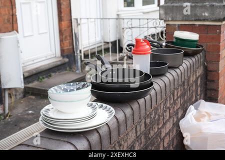 Selly Oak, Birmingham, 30 giugno 2024 - varie pentole, padelle e piatti sono stati lasciati su un muro. - Le strade residenziali di Birmingham sono state trasformate in discarica mentre gli studenti si spostano di casa alla fine dei loro contratti. La maggior parte degli studenti frequenta l'Università di Birmingham, che si trova a circa 800 metri dalle strade abitative terrazzate di Selly Oak. Le strade sono state acquistate principalmente da proprietari terrieri che le affittano ai laureandi con una fila di insegne "in affitto". Credito: Interrompi stampa Media/Alamy Live News Foto Stock