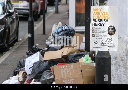 Selly Oak, Birmingham, 30 giugno 2024 - Un poster che chiede alla gente perché stanno scaricando rifiuti con rifiuti scaricati sullo sfondo. - Le strade residenziali di Birmingham sono state trasformate in discarica mentre gli studenti si spostano di casa alla fine dei loro contratti. La maggior parte degli studenti frequenta l'Università di Birmingham, che si trova a circa 800 metri dalle strade abitative terrazzate di Selly Oak. Le strade sono state acquistate principalmente da proprietari terrieri che le affittano ai laureandi con una fila di insegne "in affitto". Credito: Interrompi stampa Media/Alamy Live News Foto Stock