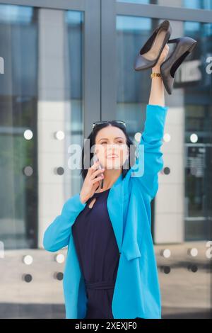 Imprenditrice felice ed entusiasta, vincitrice in piedi per strada in città che parla al telefono e celebra il successo del lavoro o gli obiettivi finanziari. Foto Stock