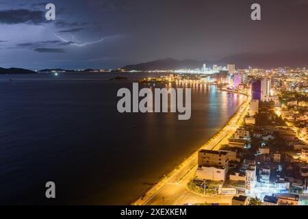 Cielo buio e tempestoso drammatico e fulmini sulla baia di Nha Trang nel Mar Cinese meridionale nella provincia di Khanh Hoa di notte in Vietnam. Foto Stock