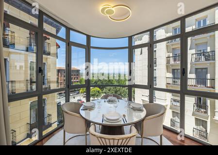 Una sala da pranzo con tavoli rotondi in legno e sedie di design minimalista con stoviglie in argento classico. Foto Stock