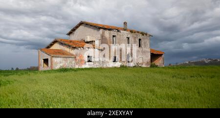 Vecchia casa colonica con potenziale ristrutturazione su una collina verde Foto Stock