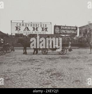 Foto d'epoca di una fila di carrozze trainate da cavalli (britzka) con passeggeri, in piedi di fronte ai cartelloni pubblicitari delle famose terme di Sandunóvskie (Sanduny) in via Neglinnaya. Mosca, Impero russo. 1898 Foto Stock