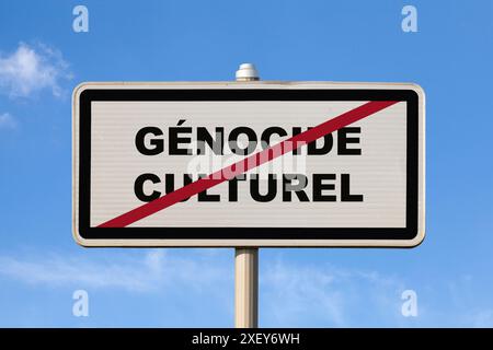Un cartello francese di uscita della città contro un cielo blu con scritto al centro in francese "Génocide culturel", che significa in inglese "genocidio culturale". Foto Stock