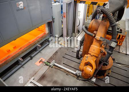 Robot che introduce i materiali nel forno e li porta successivamente alla pressa, alla cella di stampaggio a caldo, all'unità industriale, all'industria automobilistica, al centro tecnologico Foto Stock