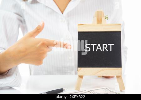 Una donna che indica una lavagna con la parola Start Foto Stock