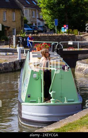 Donna su una barca a vela che usa il telefono cellulare che passa attraverso le chiuse di Bradford sul canale Kennet e Avon a Bradford su Avon Wiltshire Foto Stock
