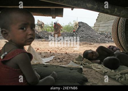 Bambini sotto l'ombra di un camion in attesa della madre che lavora in un campo di mattoni ad Amin Bazar, Dhaka, Bangladesh. 30 aprile 2007 Foto Stock