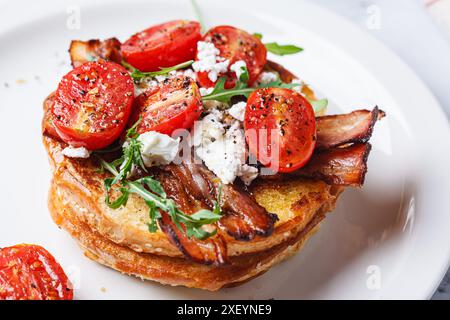 Toast alla francese con pancetta, pomodoro, rucola e feta, primo piano. Ricetta per la colazione all'americana. Foto Stock