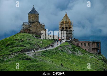 Stepantsminda, Georgia - 30 giugno 2024: Persone che visitano la chiesa della Trinità di Gergeti sul monte Kazbek a Stepantsminda, Georgia. Foto Stock