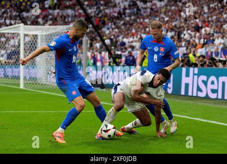 L'inglese Jude Bellingham (centro) combatte per il pallone con la slovacca David Hancko (sinistra) e Ondrej Duda (destra) combattono per il pallone durante la UEFA Euro 2024, round of 16 match all'Arena AufSchalke di Gelsenkirchen, Germania. Data foto: Domenica 30 giugno 2024. Foto Stock