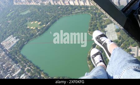 New York City esce dal volo in elicottero, elicottero che sorvola Manhattan, Stati Uniti. Piedi in sneakers, gambe in scarpe selfie pov. Avventura turistica estrema, viaggia negli Stati Uniti. Vibrazioni della telecamera. Central Park. Foto Stock