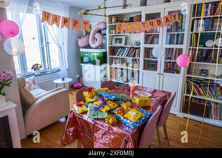 Splendida vista della camera arredata per la festa di compleanno dei bambini con regali avvolti in festività sdraiati sul tavolo. Foto Stock