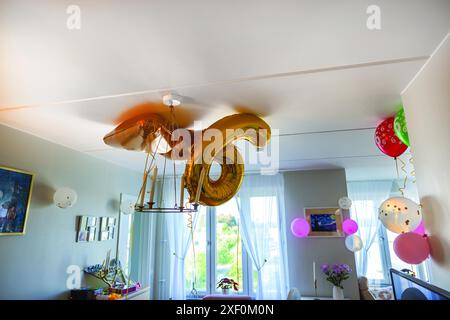 Vista ravvicinata della sala decorata per le celebrazioni, con palloncini dorati numero 6, palloncini colorati e varie decorazioni appese al soffitto Foto Stock