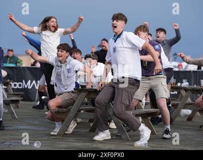 Tifosi inglesi sull'Hastings Pier nell'East Sussex, durante una proiezione della partita UEFA Euro 2024, round of 16, tra Inghilterra e Slovacchia. Data foto: Domenica 30 giugno 2024. Foto Stock