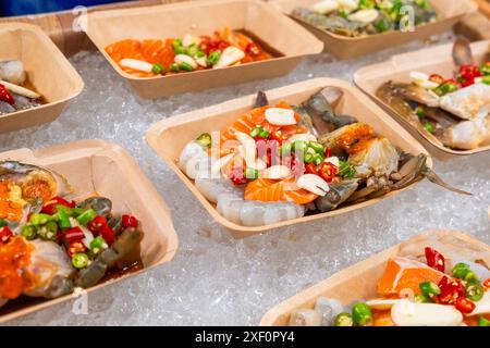 Cibo tailandese al mercato notturno. Selezione di piatti marinati a base di pesce crudo a base di salmone, gamberetti e granchi preparati per il sashimi. Cibo asiatico in Foto Stock