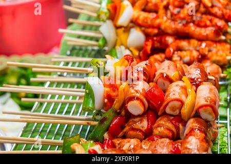 Cibo tailandese al mercato notturno. Spiedini colorati con verdure, pesce e carne. Cibo asiatico a Bangkok, Thailandia Foto Stock