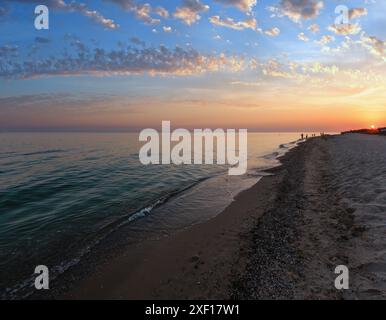 Sole al tramonto sopra autosufficienti camping nella prateria di sabbia sul mare Azov arenile (Lazurne, Regione di Kherson, Ucraina). Persone irriconoscibile. Foto Stock