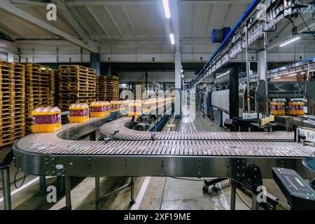 Linea di produzione di imbottigliamento di bevande in bottiglie di plastica e imballaggio. Foto Stock