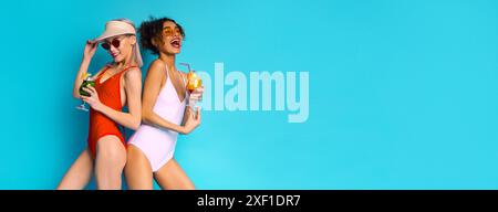 Due donne in costume da bagno bevono cocktail su sfondo blu Foto Stock