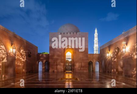 Cortile interno della grande Moschea del Sultano Qaboos, pareti decorate e minareto luccicante di notte, Mascate. Oman Foto Stock