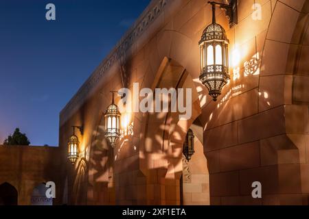 Cortile interno della grande Moschea del Sultano Qaboos con pareti decorate con lampade che brillano di notte, Mascate. Oman Foto Stock