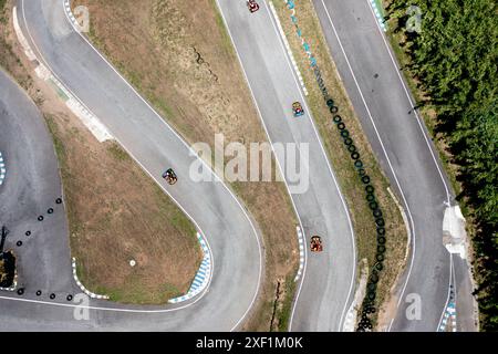 Vista dall'alto dall'alto dell'auto da corsa con droni su una pista tortuosa. Nuvoloso giorno d'estate. Gare di kart sport motoristico a ruote libere. Gara di go-kart Foto Stock