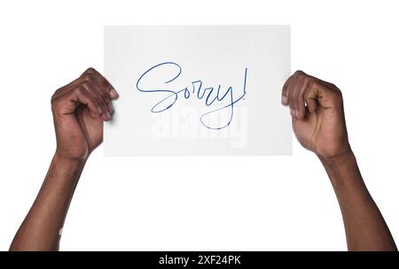 Uomo che tiene un foglio di carta con una parola di scuse su sfondo bianco, primo piano Foto Stock