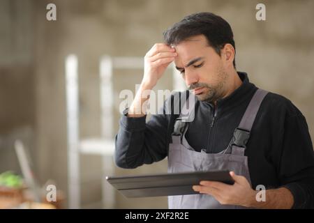 Preoccupava gli operai edili che controllavano il tablet in una casa Foto Stock