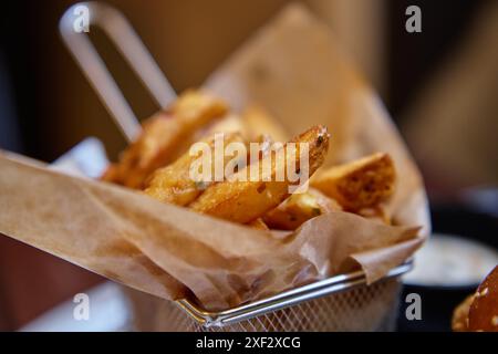 Primo piano di patatine fritte croccanti servite nel cestino di carta del ristorante Foto Stock