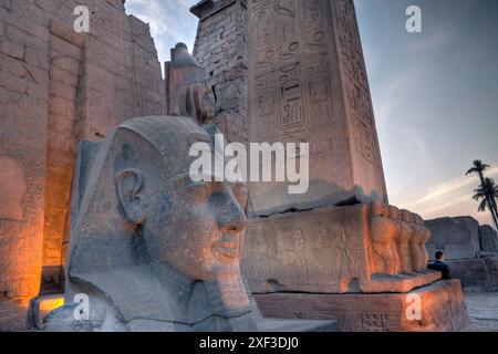 Ingresso illuminato del tempio di Luxor con statua di Ramses II e obelisco, Egitto Foto Stock