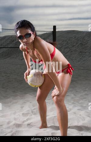 La signora in bikini gioca a pallavolo in spiaggia Foto Stock