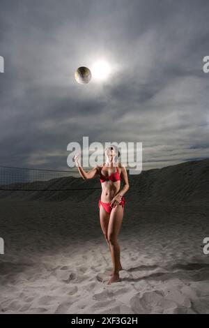 La signora in bikini gioca a pallavolo in spiaggia Foto Stock