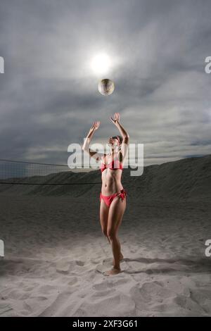 La signora in bikini gioca a pallavolo in spiaggia Foto Stock