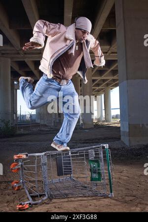 Un rapper e ballerino afroamericano si trova sotto un ponte in un paesaggio urbano. Foto Stock