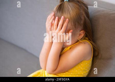 bambino piccolo di 5 anni, ragazza bionda piange, copre il viso, diagnosi precoce e intervento, supporto per le persone con autismo, atteggiamento protettivo, compl Foto Stock