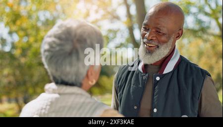 Amore, coppia felice e senior nel parco per camminare, calmare e parlare in pensione nella natura o nella foresta. Partner, diversificato e supporto o fiducia per l'uomo e. Foto Stock