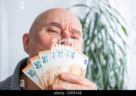 uomo soddisfatto in possesso di euro, euro in tifoso, gioisce del successo, anticipa su cosa spenderlo, incoraggiando un buon comportamento finanziario, aw economico Foto Stock