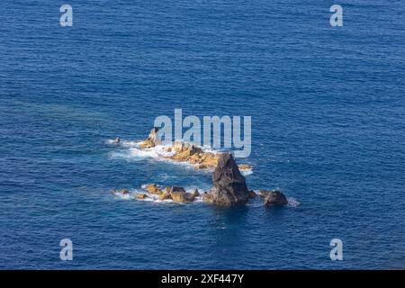 Un'isola rocciosa si trova in mezzo all'oceano Foto Stock