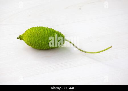 Verdura verde spinosa (Momordica dioica) su fondo di legno. Vista dall'alto. Foto Stock