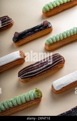 Selezione di eclari, diversi Eclair deliziosi su sfondo beige Foto Stock