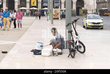 Lisbona Portogallo: Busker in Piazza del commercio, una popolare attrazione turistica. L'uomo sta usando lattine vuote e contenitori di plastica come fusti. Foto Stock