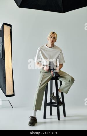 Un uomo elegante si siede su uno sgabello e cattura immagini con una fotocamera. Foto Stock